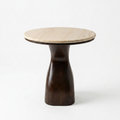 A modern side table featuring a round, light beige travertine stone top and a sculptural, tapered dark brown wooden base, photographed on a seamless white background.