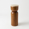 A minimalist wooden side table or pedestal with a cylindrical base and a round travertine top, featuring a mango wood finish and a contrasting light beige wood lid, set against a plain white background.