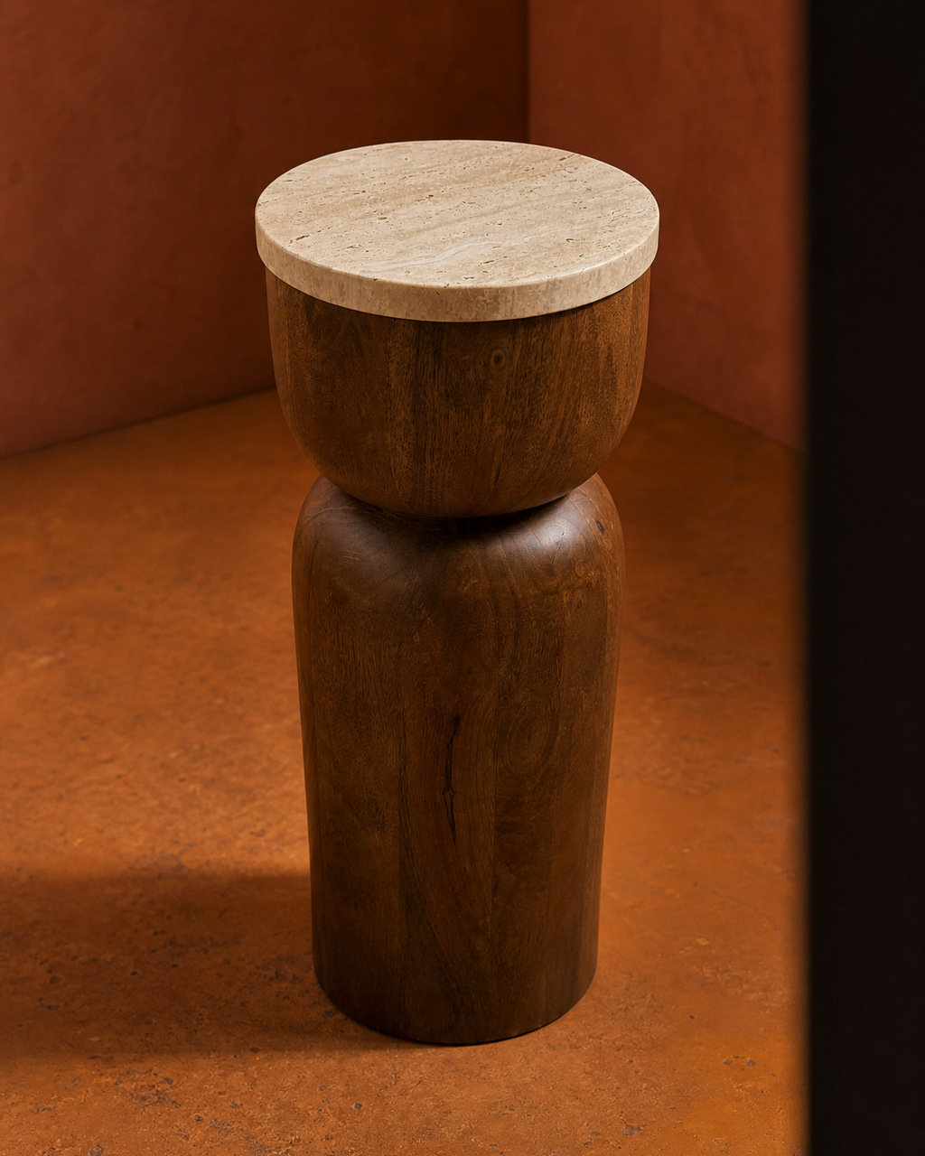 A modern two-tone wooden stool with a cylindrical brown mango wood base and a round light beige travertine stone top, set against a warm terracotta background.
