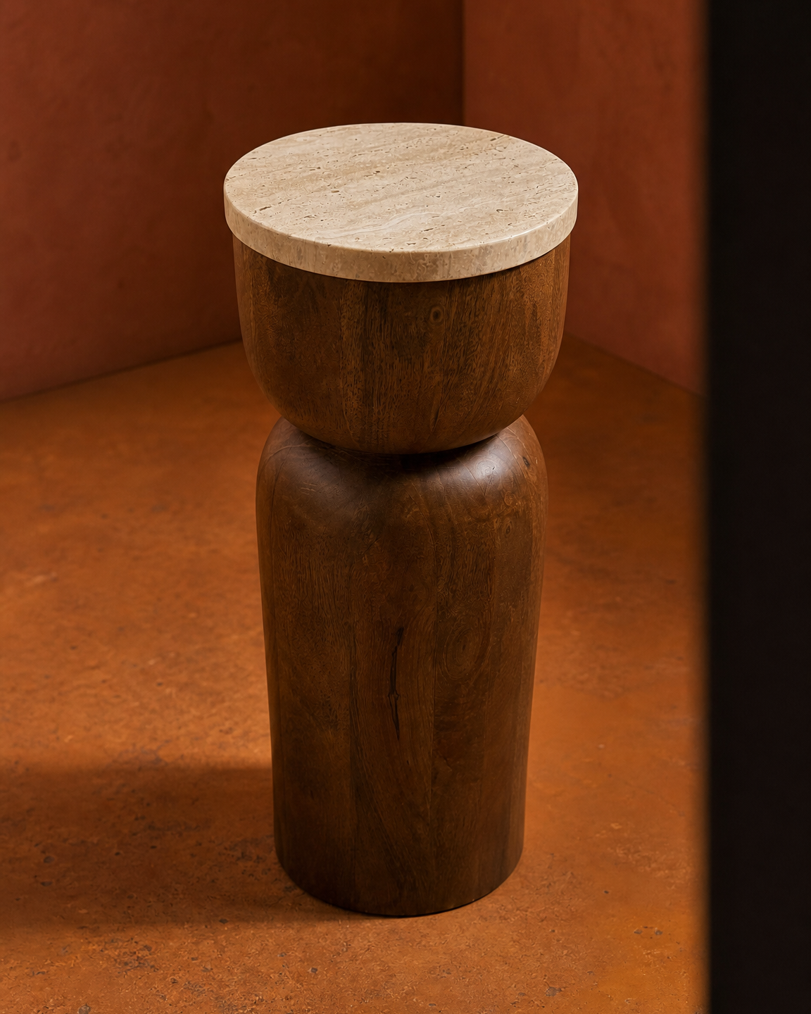 A modern two-tone wooden stool with a cylindrical brown mango wood base and a round light beige travertine stone top, set against a warm terracotta background.